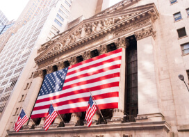 Exterior of the New York Stock Exchange building with a large American flag proudly displayed